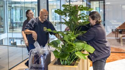 Medewerkers vullen een plantenbak en hebben duidelijk plezier tijdens het werk