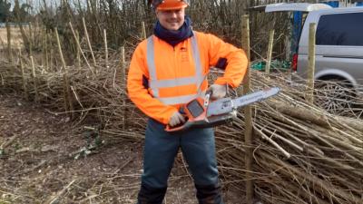Man met elektrische zaag en oranje veiligheidsjas