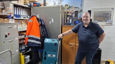 Tom Koppen in zijn eigen werkomgeving met een steekwagen vol met gereedschapskoffers