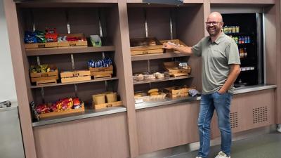 Hans Huberts voor een kast met snoep, koek en broodjes.