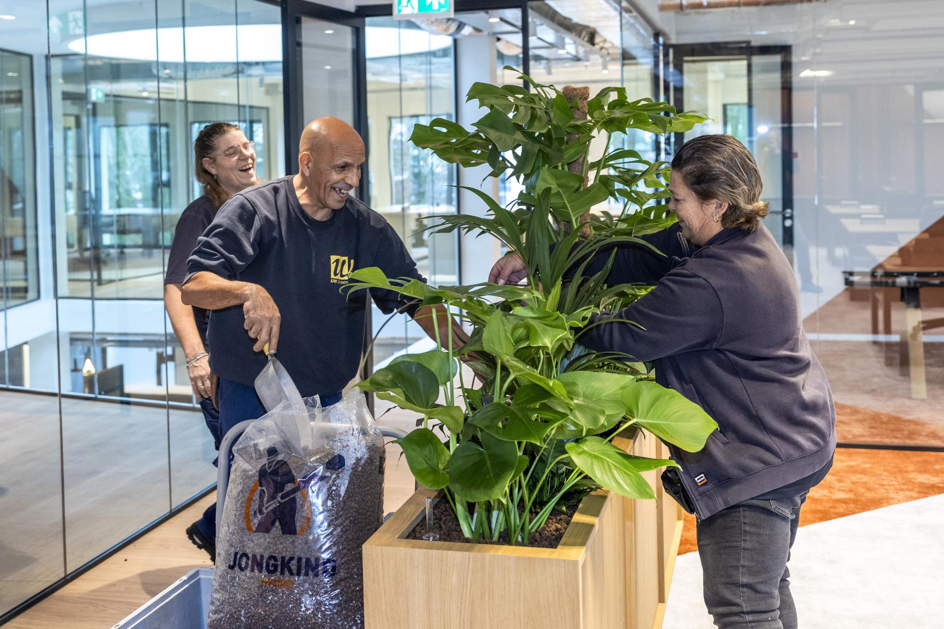 Medewerkers vullen een plantenbak en hebben duidelijk plezier tijdens het werk