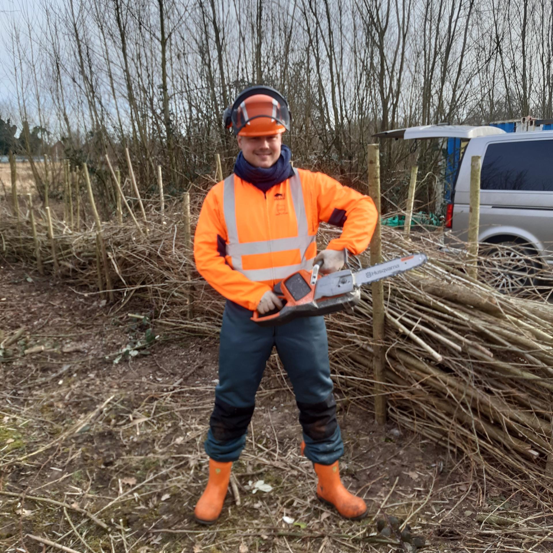 Man met elektrische zaag en oranje veiligheidsjas
