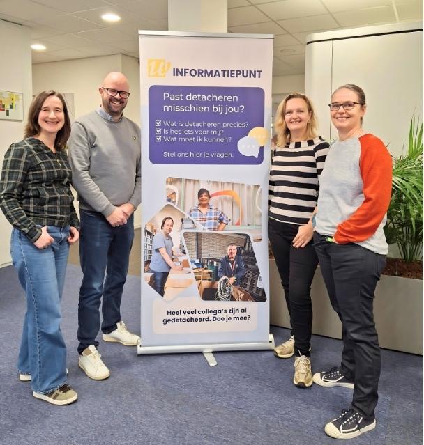 De detacheringsconsulenten staan voor een banner met informatie over het spreekuur