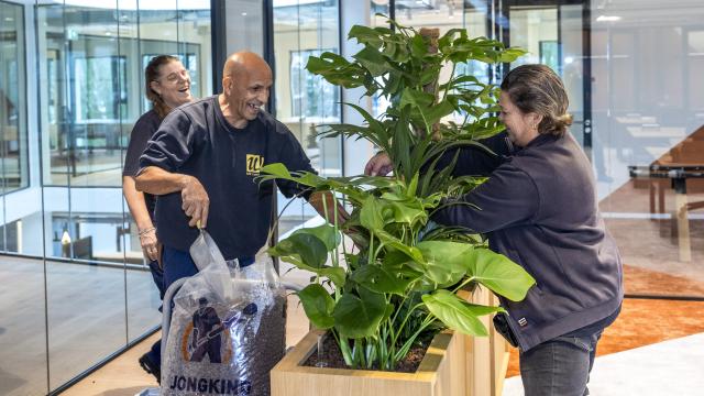 Medewerkers vullen een plantenbak en hebben duidelijk plezier tijdens het werk